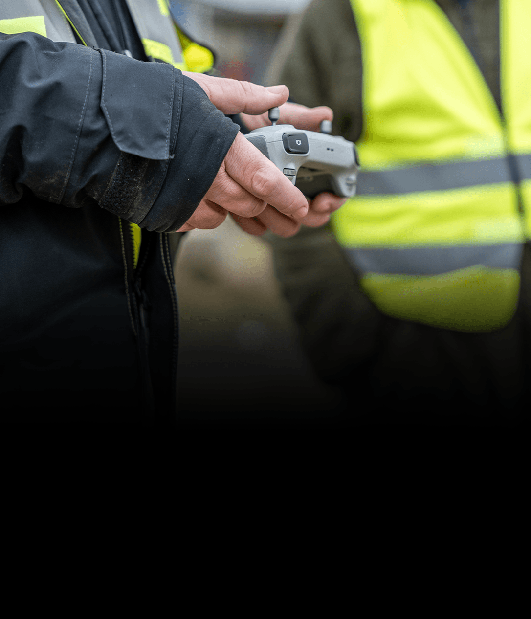 En person i arbetskläder håller i en drönarkontroll, redo att styra enheten.