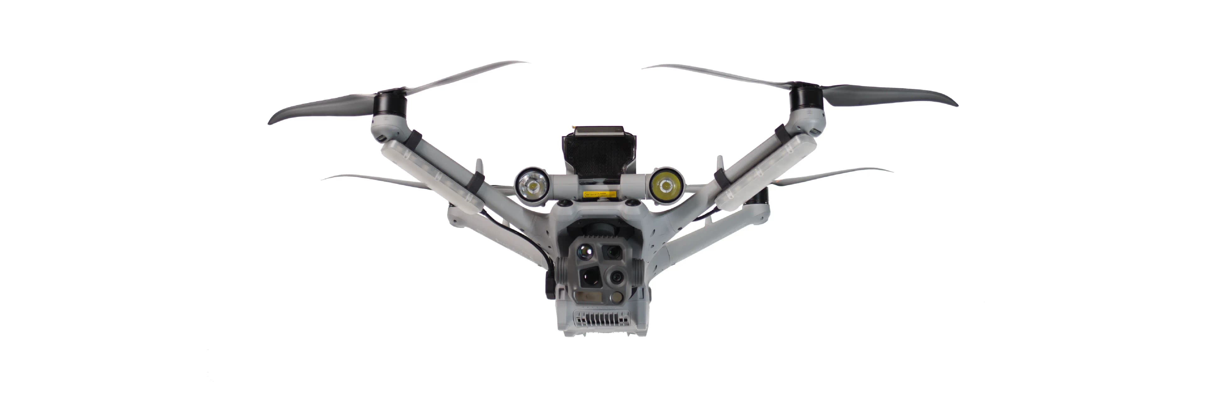 En avancerad drönare med flera sensorer och propellrar svävar mot en vit bakgrund.