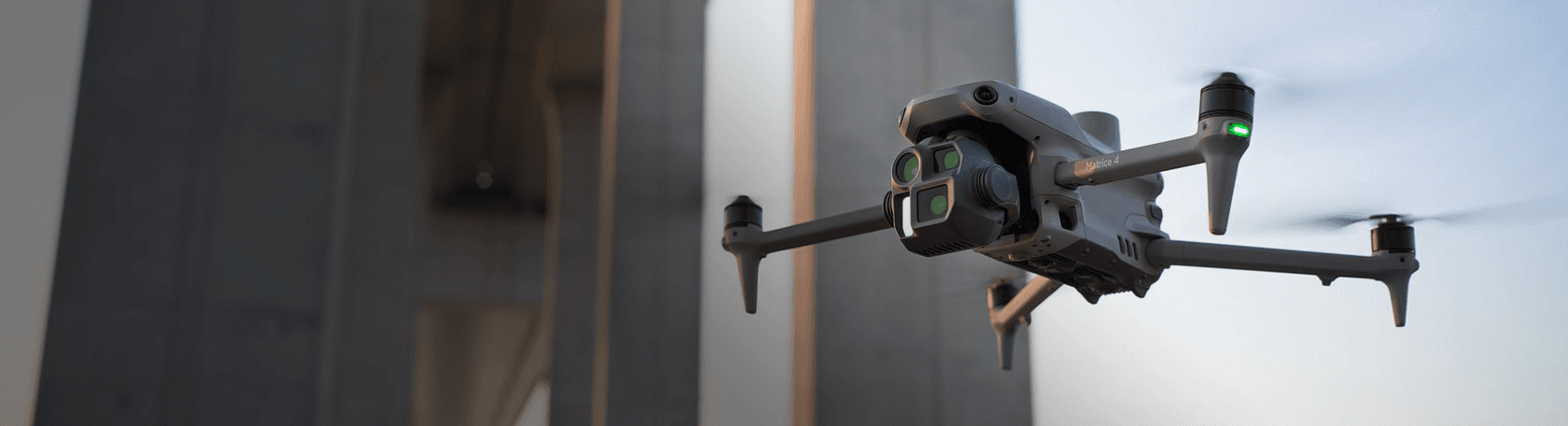 En drönare svävar framför en stor betongstruktur i skymningen, redo för inspektion eller övervakning.