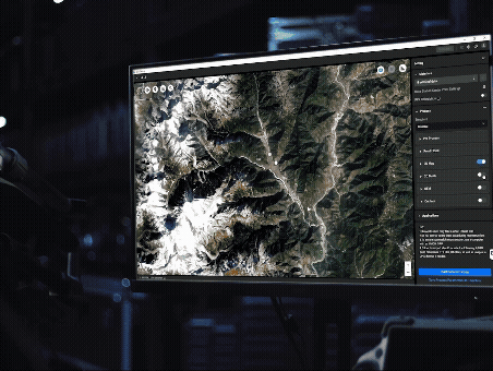 En datorskärm visar en detaljerad satellitbild av ett bergigt landskap i en mörk, teknologisk miljö.