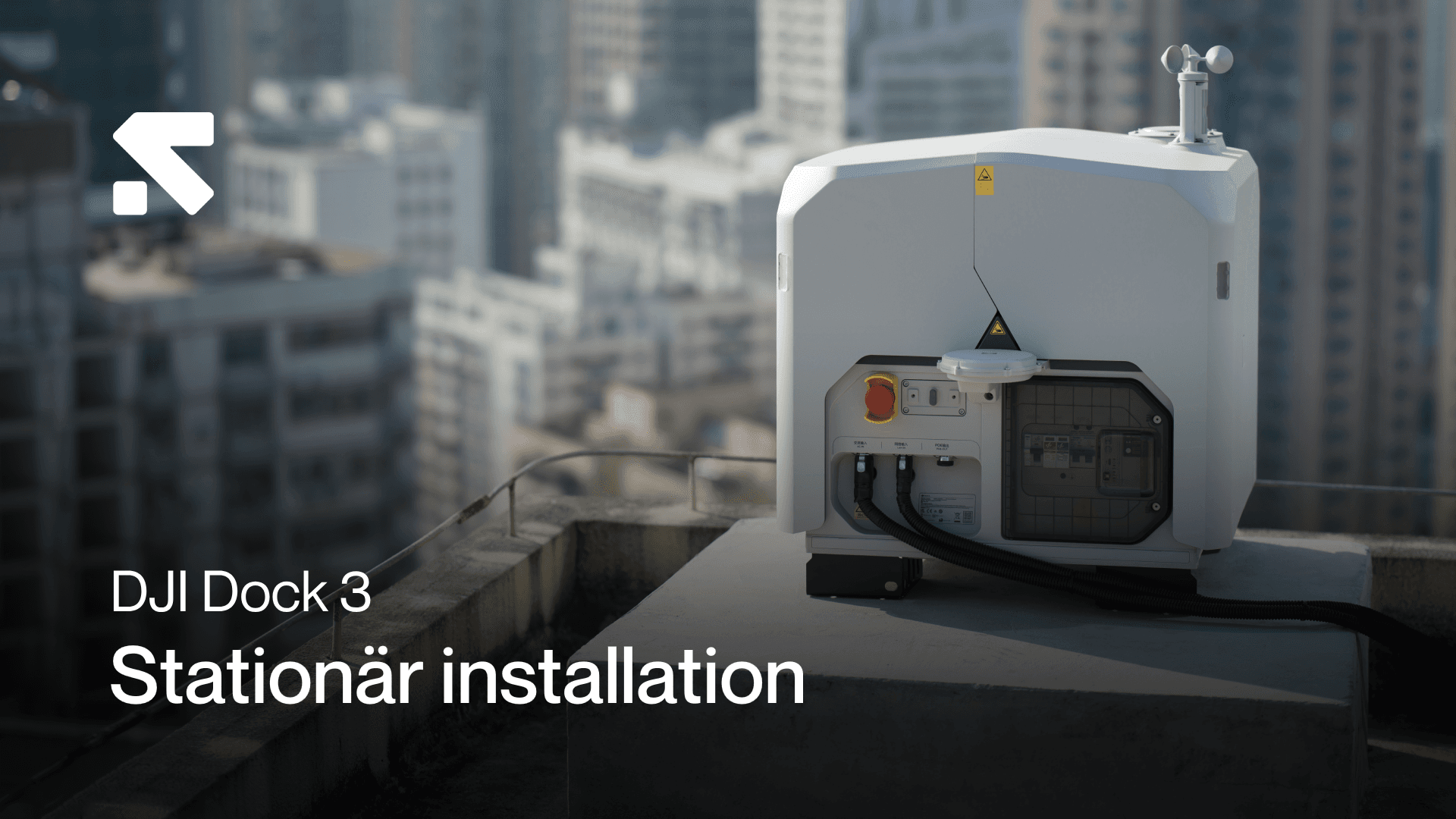 En DJI Dock 3-enhet är installerad på ett tak i en stadsmiljö, omgiven av höghus.