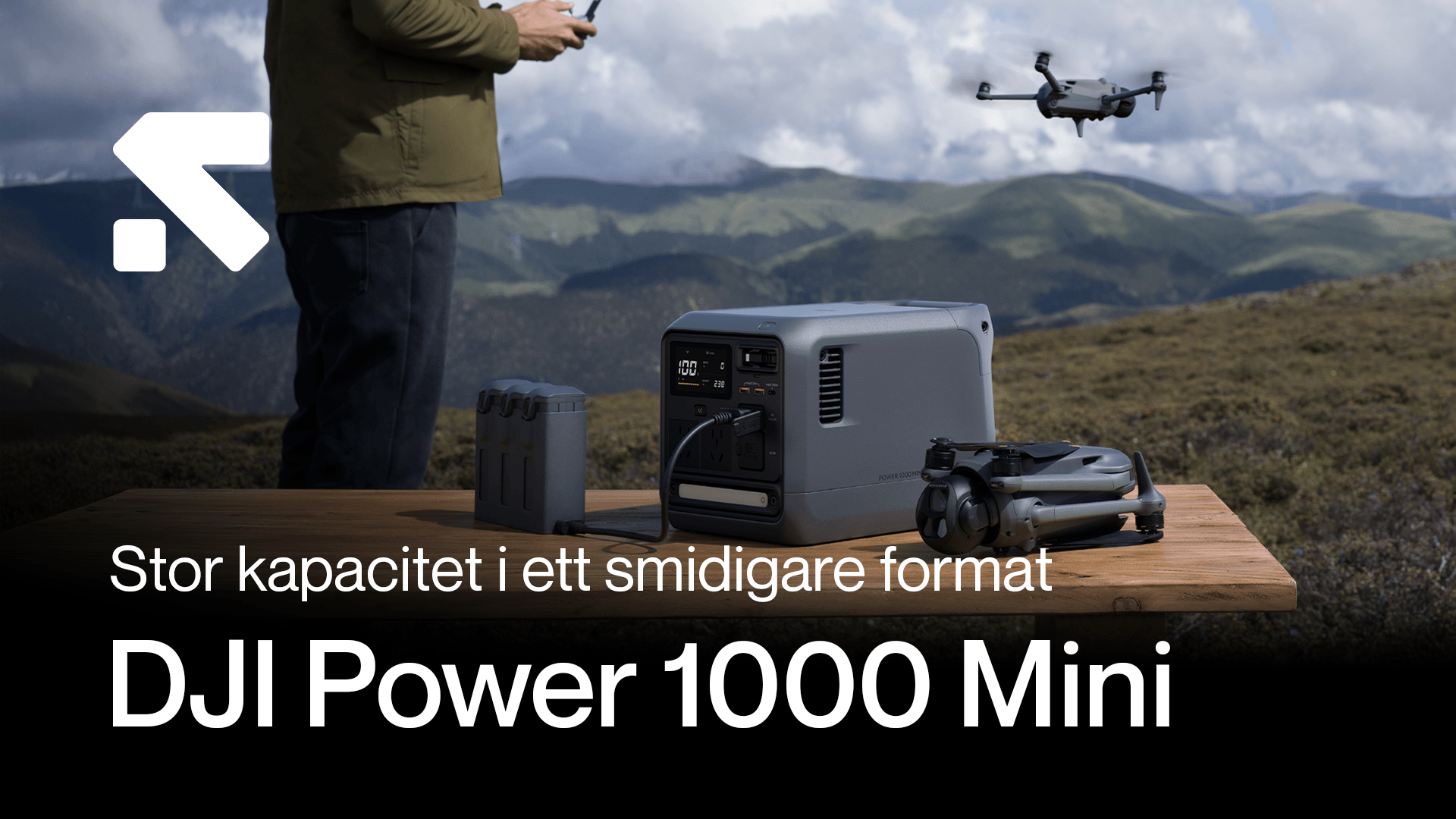 En person står vid ett bord utomhus med en DJI Power 1000 Mini, en drönare och batterier, med berg i bakgrunden. Stor kapacitet - Mini 1000.png
