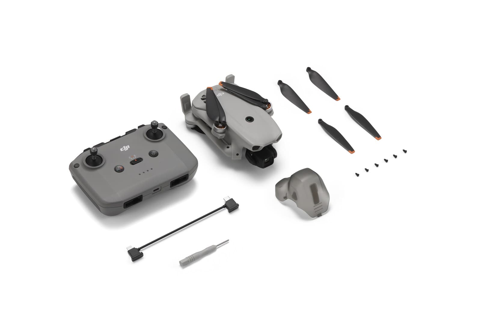 En drönare med tillhörande fjärrkontroll, propellrar och verktyg ligger organiserade på en vit yta.