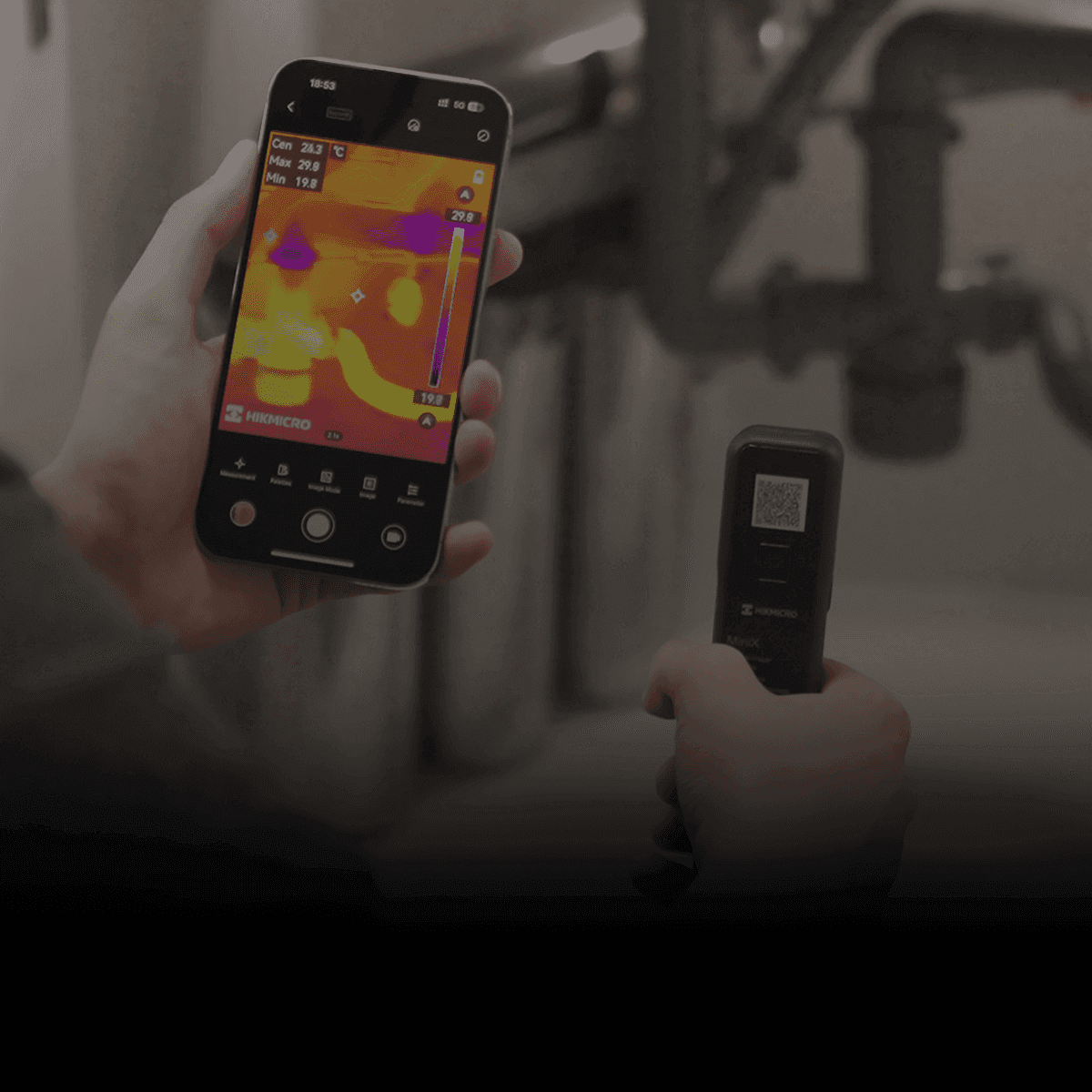 En person använder en smartphone för att visa en termisk bild av ett rörsystem, med hjälp av en handhållen termisk sensor.