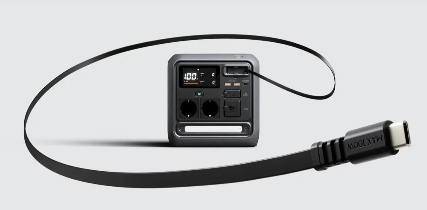 En kompakt kraftstation med (DJI Power 1000 Mini) flera uttag och en ansluten USB-C-kabel, mot en ren bakgrund.