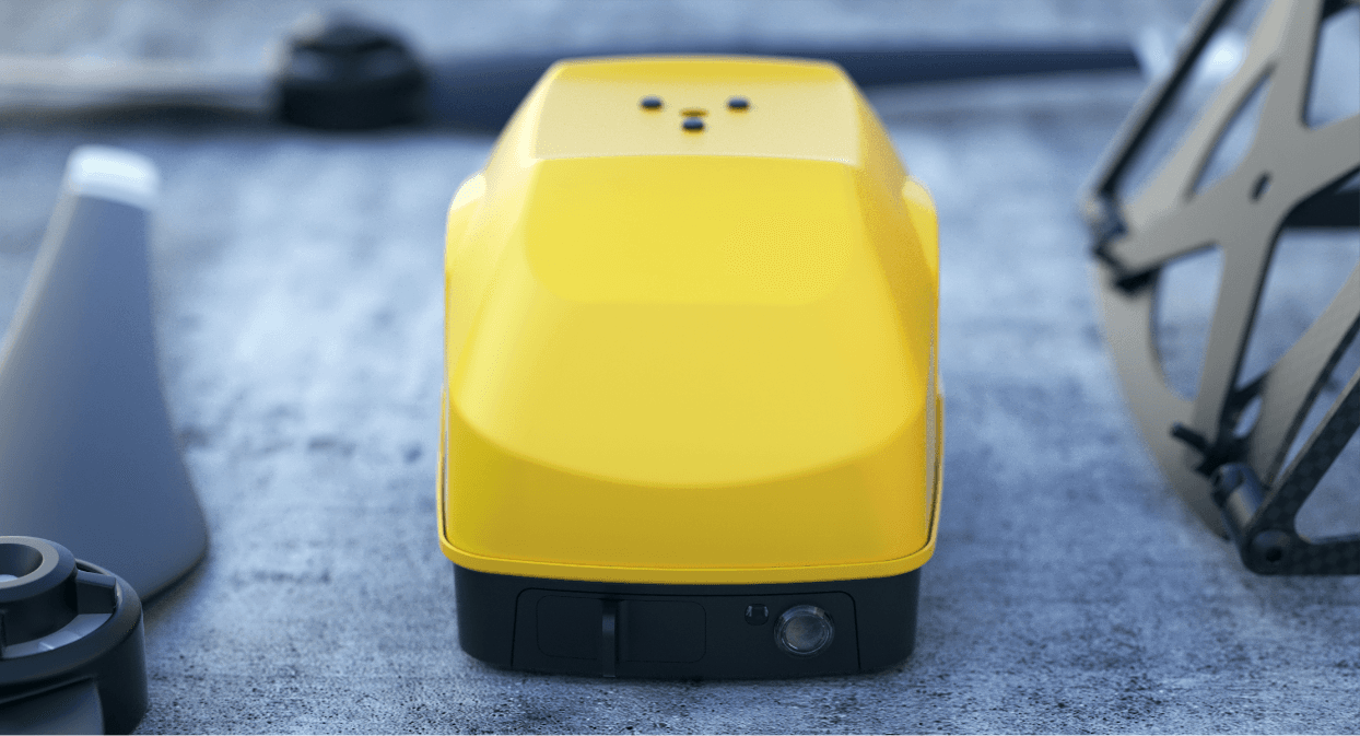 En gul fallskärm för drönare ligger på en betongyta, omgiven av propellerblad och drönardelar.