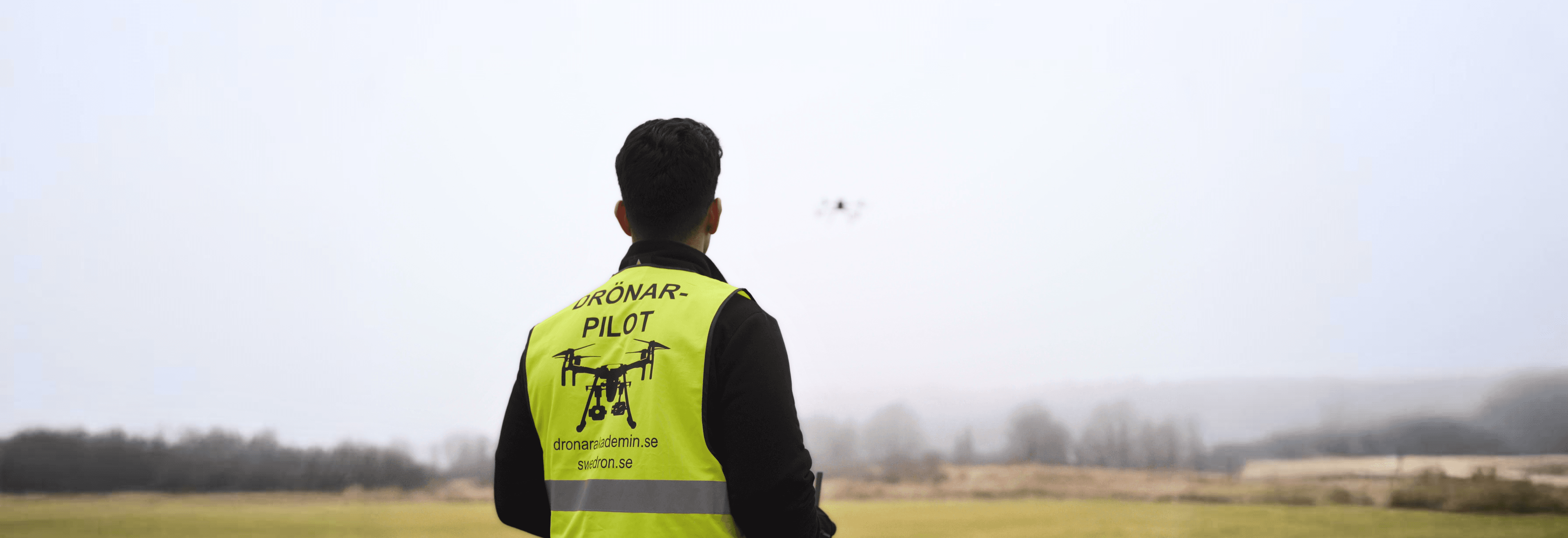 Drönarpilot i varselväst som flyger drönare