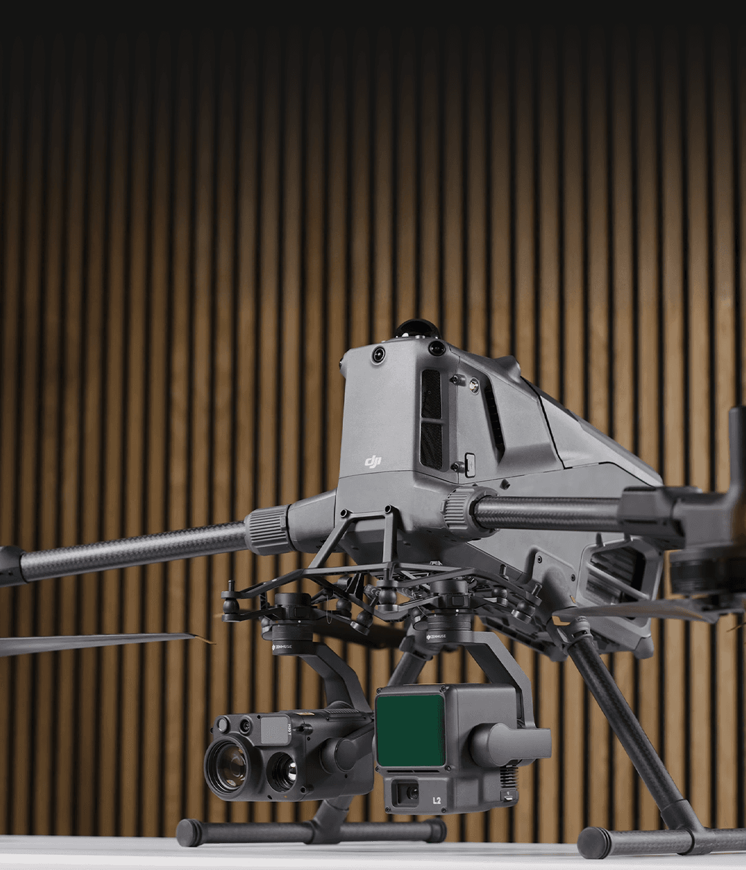 En avancerad drönare utrustad med flera kameror och sensorer står på en yta, mot en bakgrund av träpaneler.