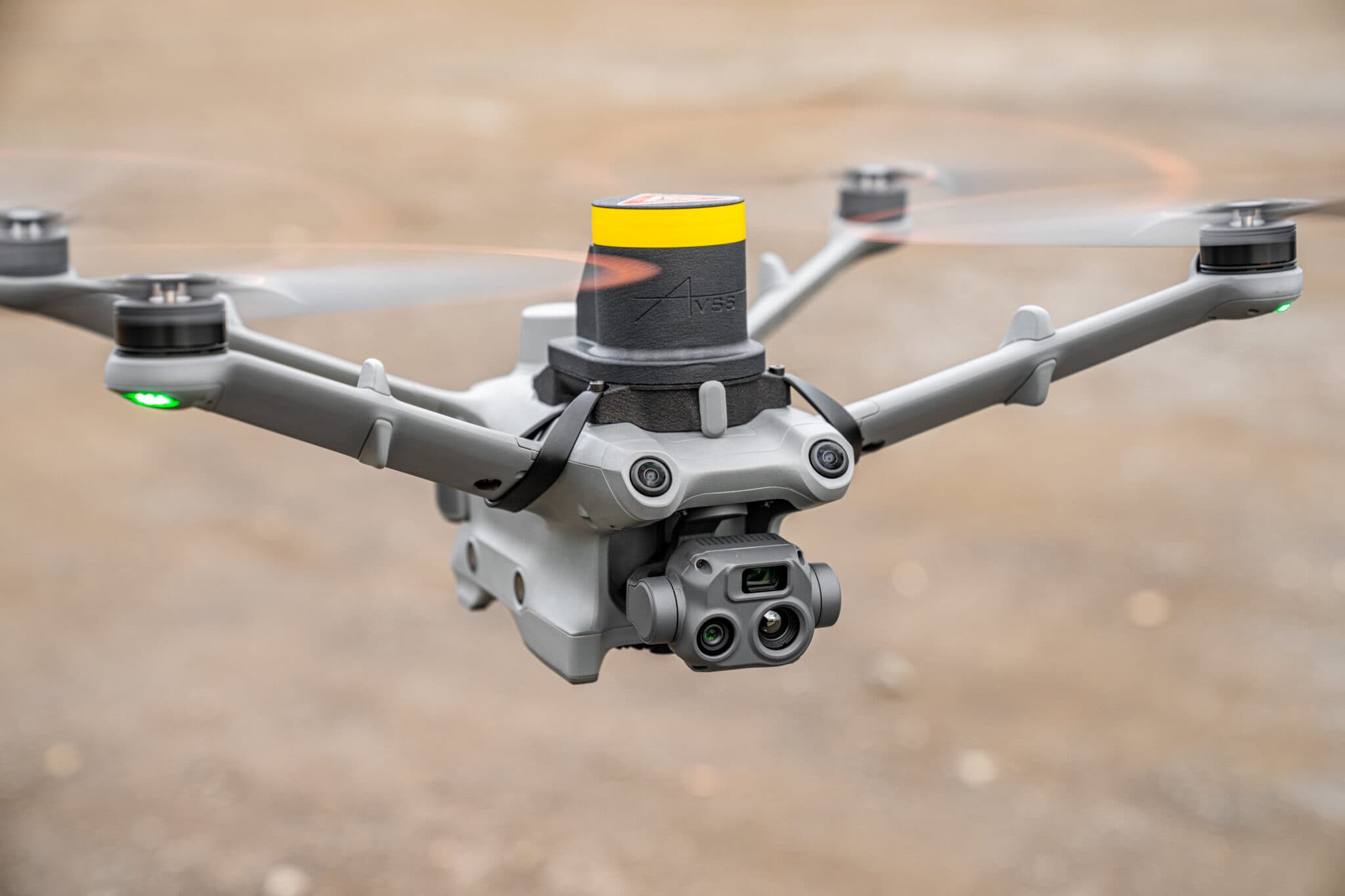 En avancerad drönare svävar i luften med roterande propellrar och kamerautrustning, redo för inspektion eller övervakning.