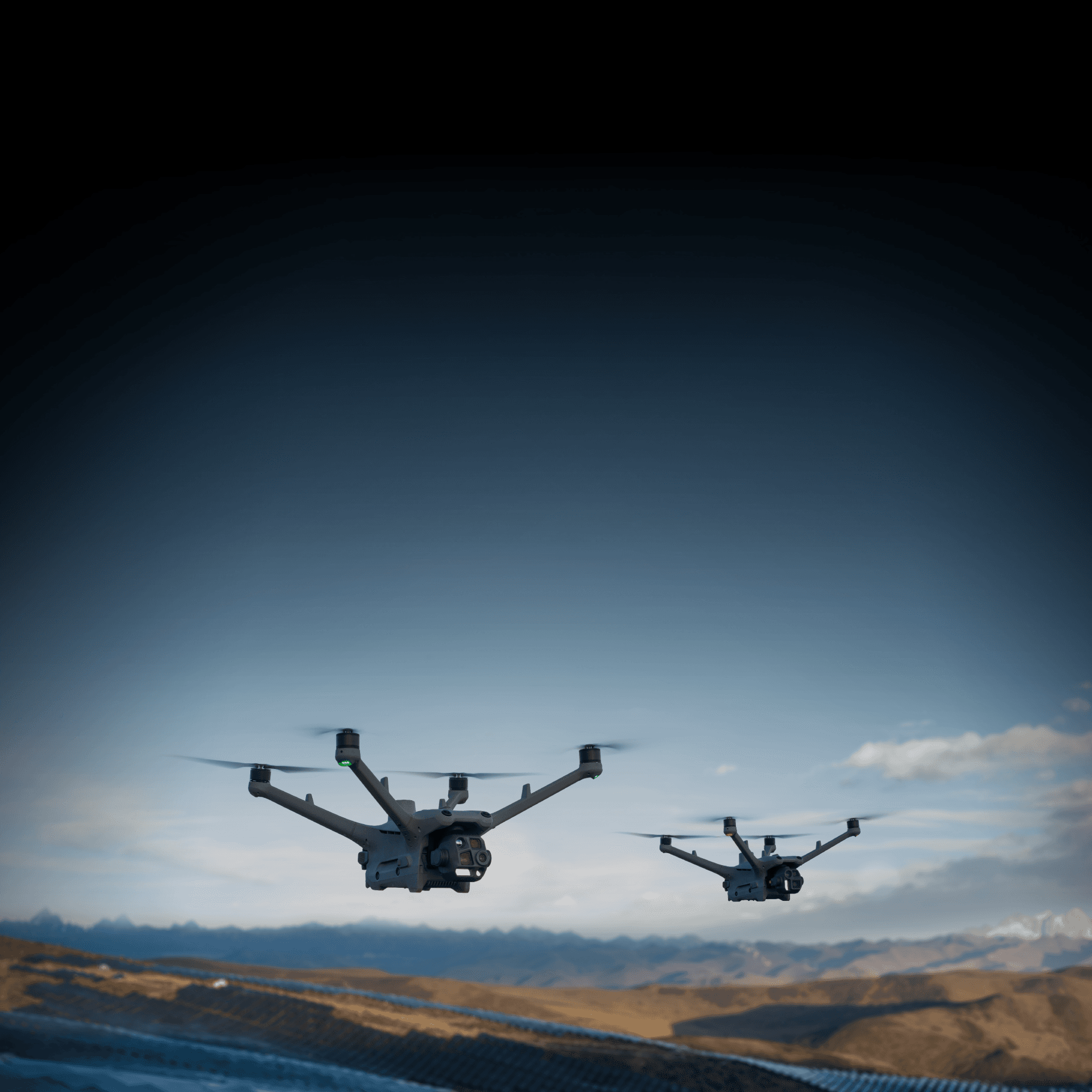 Två drönare svävar över ett ökenlandskap under en klar himmel.