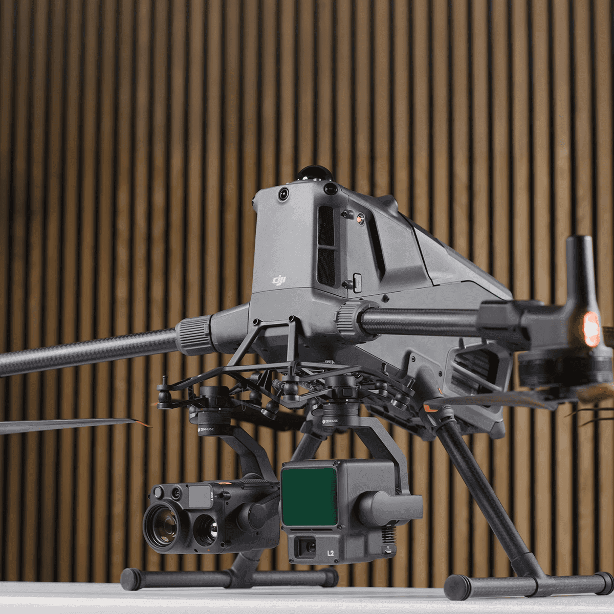 En avancerad drönare med flera sensorer och kameror visas mot en träpanelbakgrund.