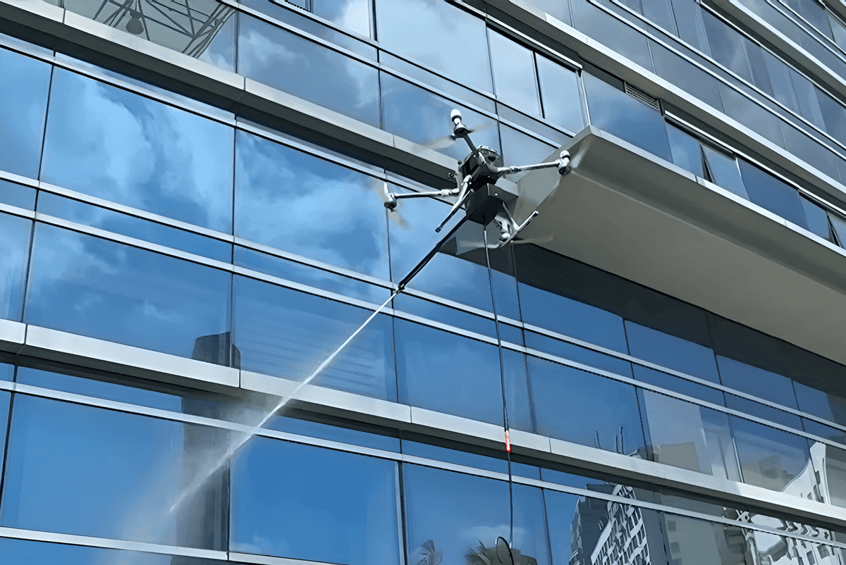 En drönare rengör fönstren på en modern glasbyggnad med en högtrycksslang.