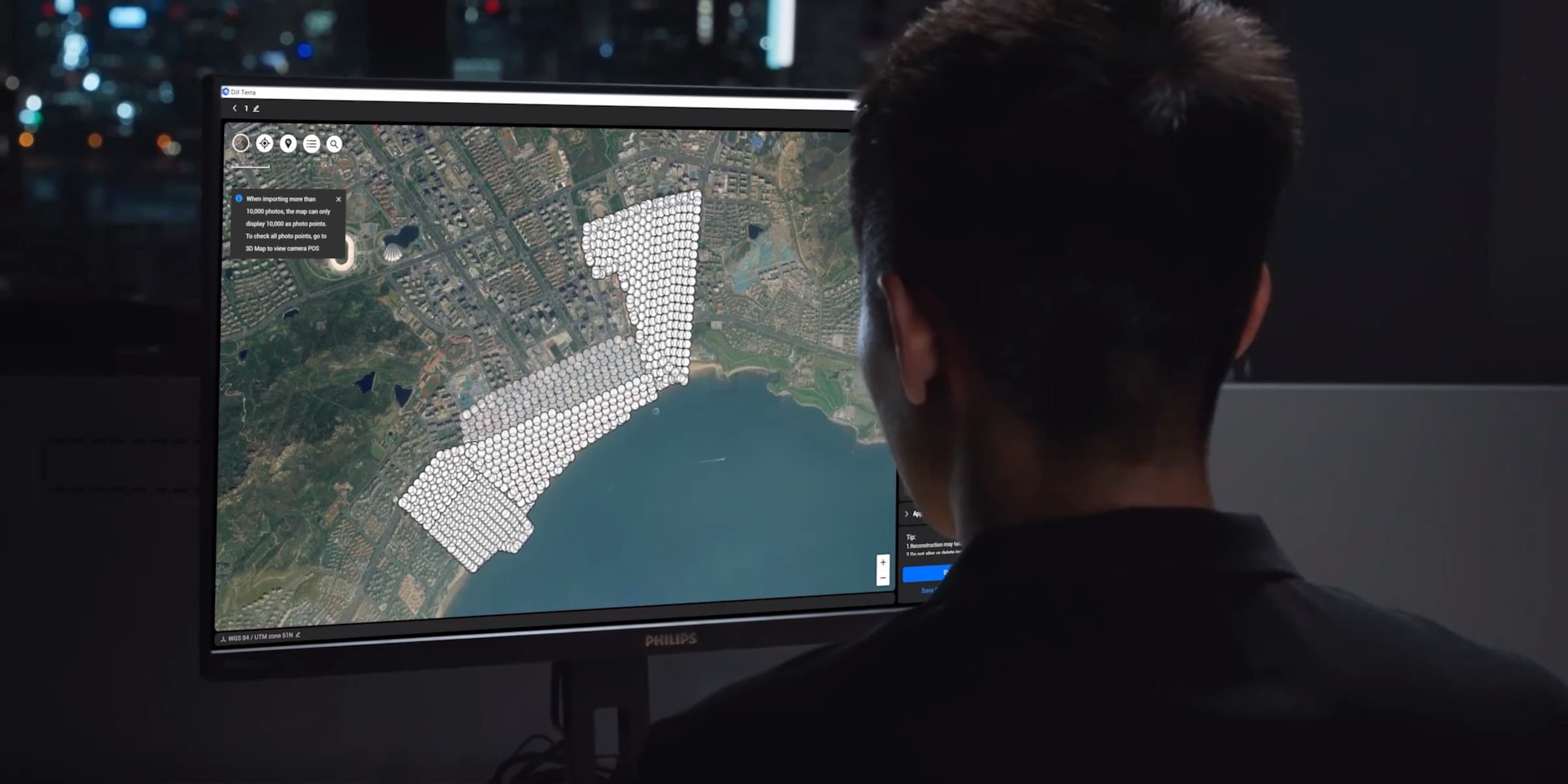 En person analyserar en detaljerad karta med markerade områden på en datorskärm i ett mörkt rum.